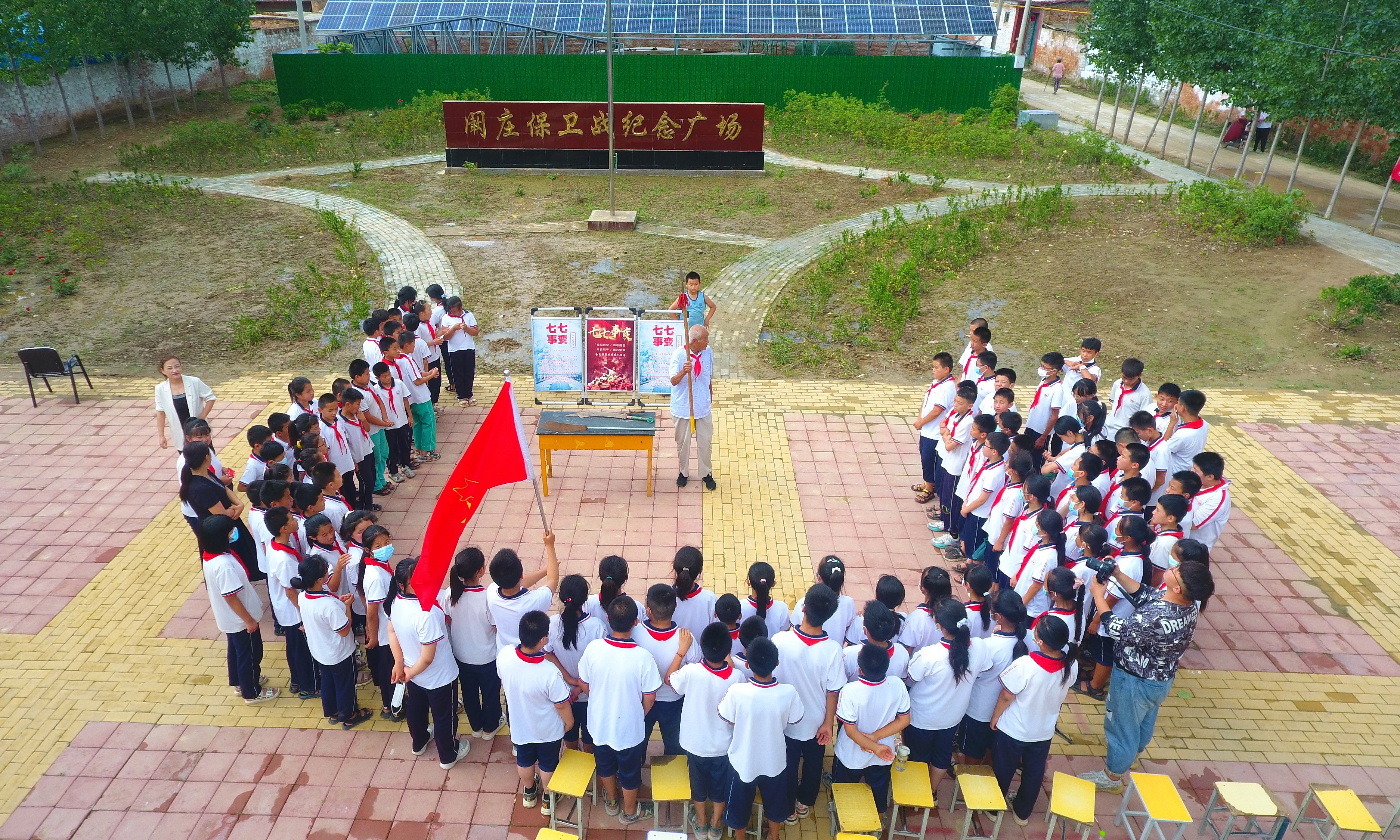 2022年7月6日，山東省聊城市，在茌平區(qū)菜屯鎮(zhèn)闞莊村的闞莊保衛(wèi)戰(zhàn)紀念廣場，闞莊保衛(wèi)戰(zhàn)親歷者王光木老人，為小學生們講述抗戰(zhàn)故事，展示大刀、長矛。